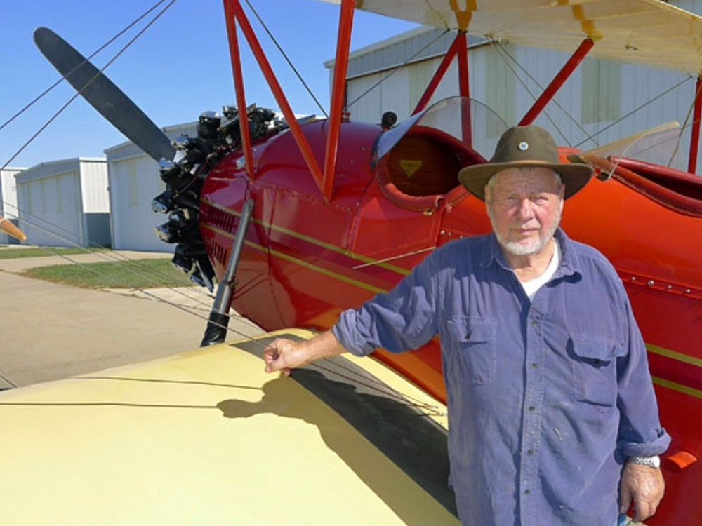 john cournoyer in front of red and yellow bi-plane