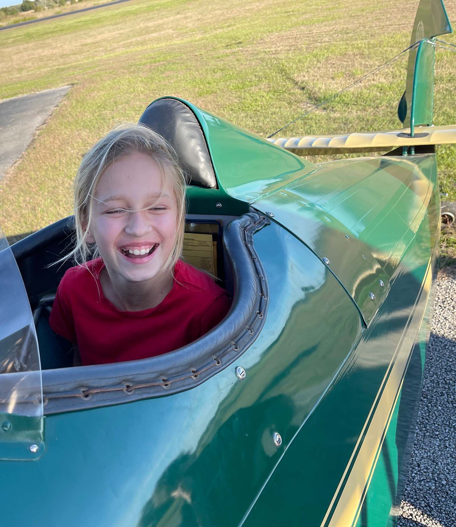close up of smiling girl in the open cockpit of a 1929 fleet biplane