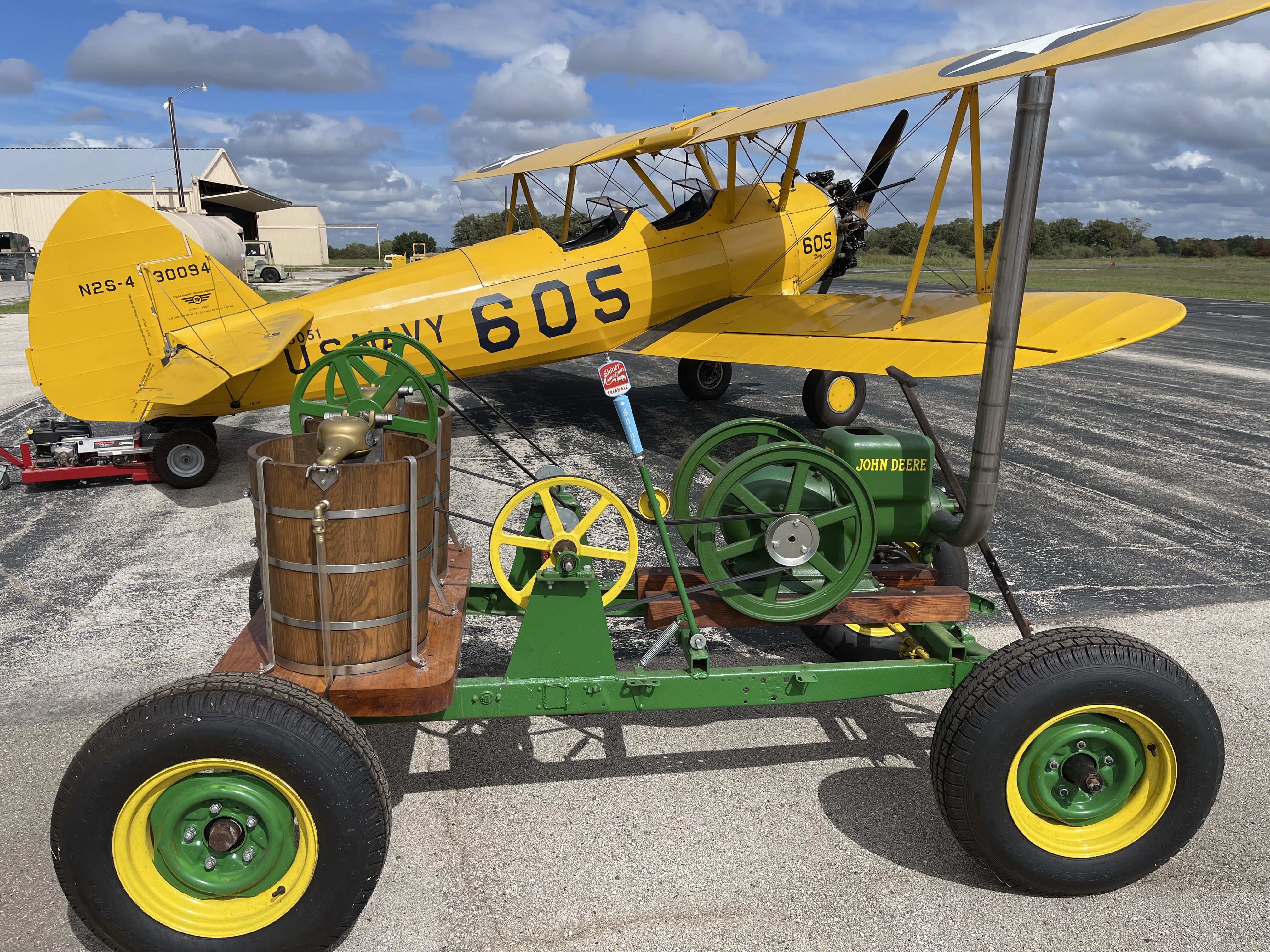 a green and yellow frame on wheels with an engine mounted on top sites on an airport runway.