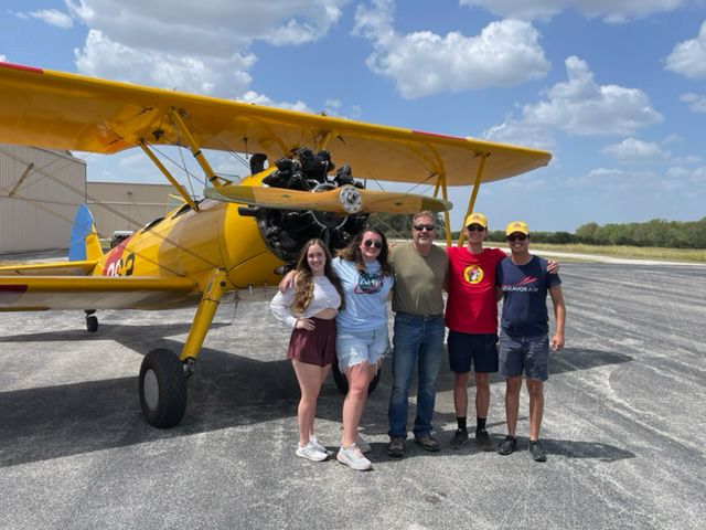 parks college kids standing with jim baker in front of a yellow stearman