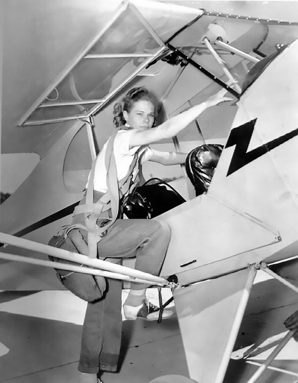 1950s young woman in saddle shoes stepping into a piper cub plane