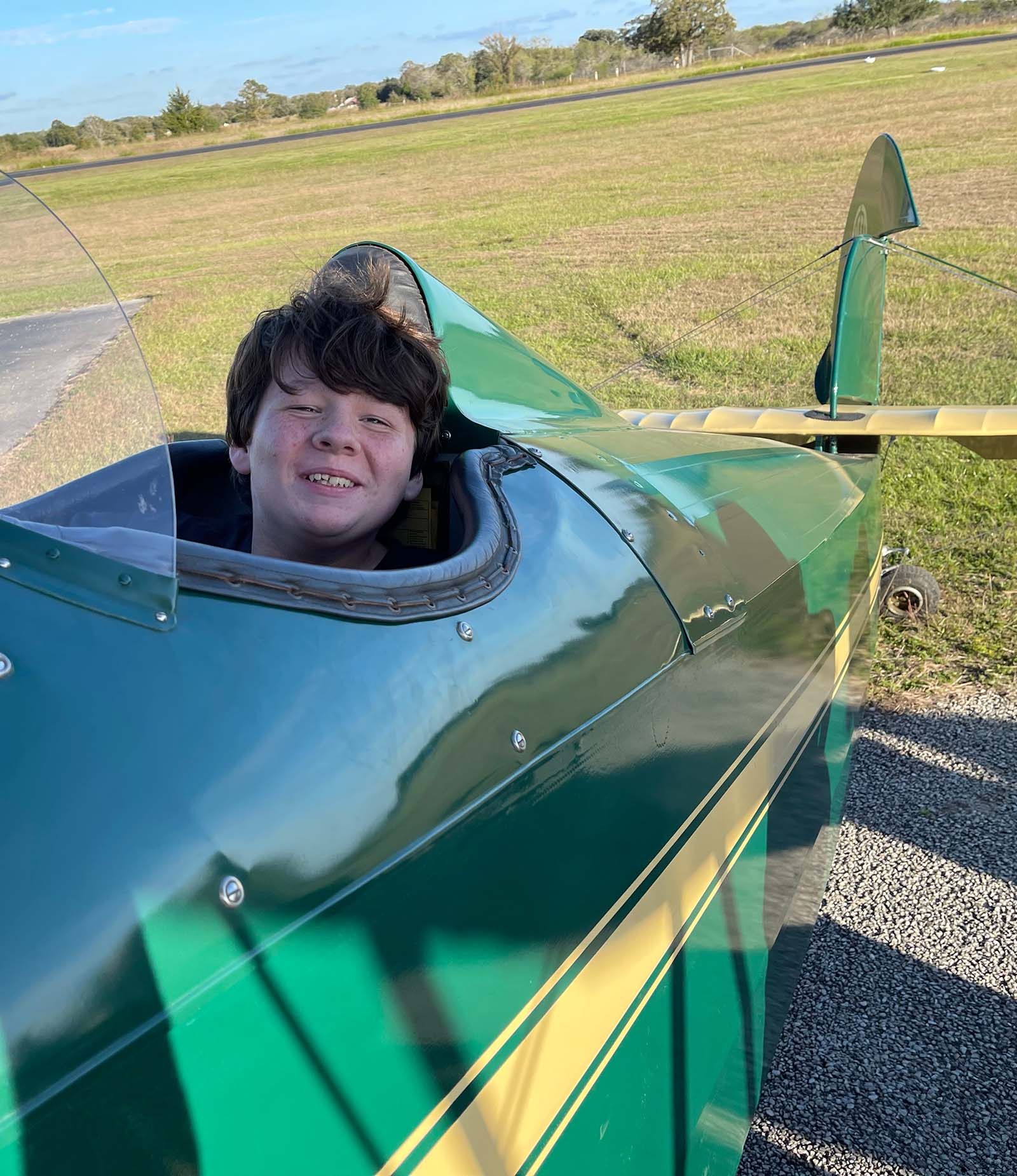 close up of smiling boy in the open cockpit of a 1929 fleet biplane