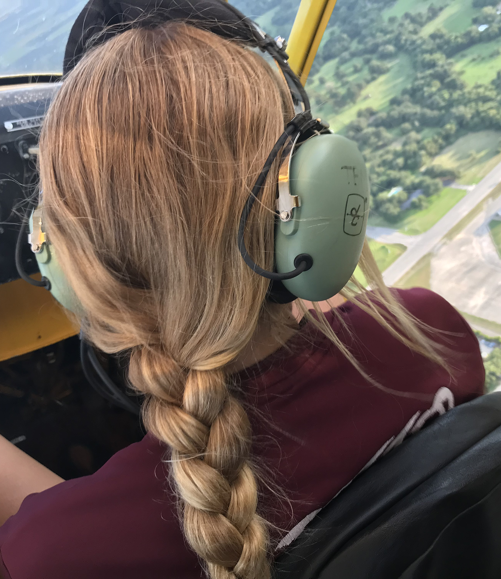 young man wearing headset in front seat of piper cub, turning around and smiling