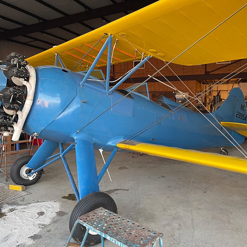 three-quarter view of waco UPF-7 in hangar. blue body with yellow wings.